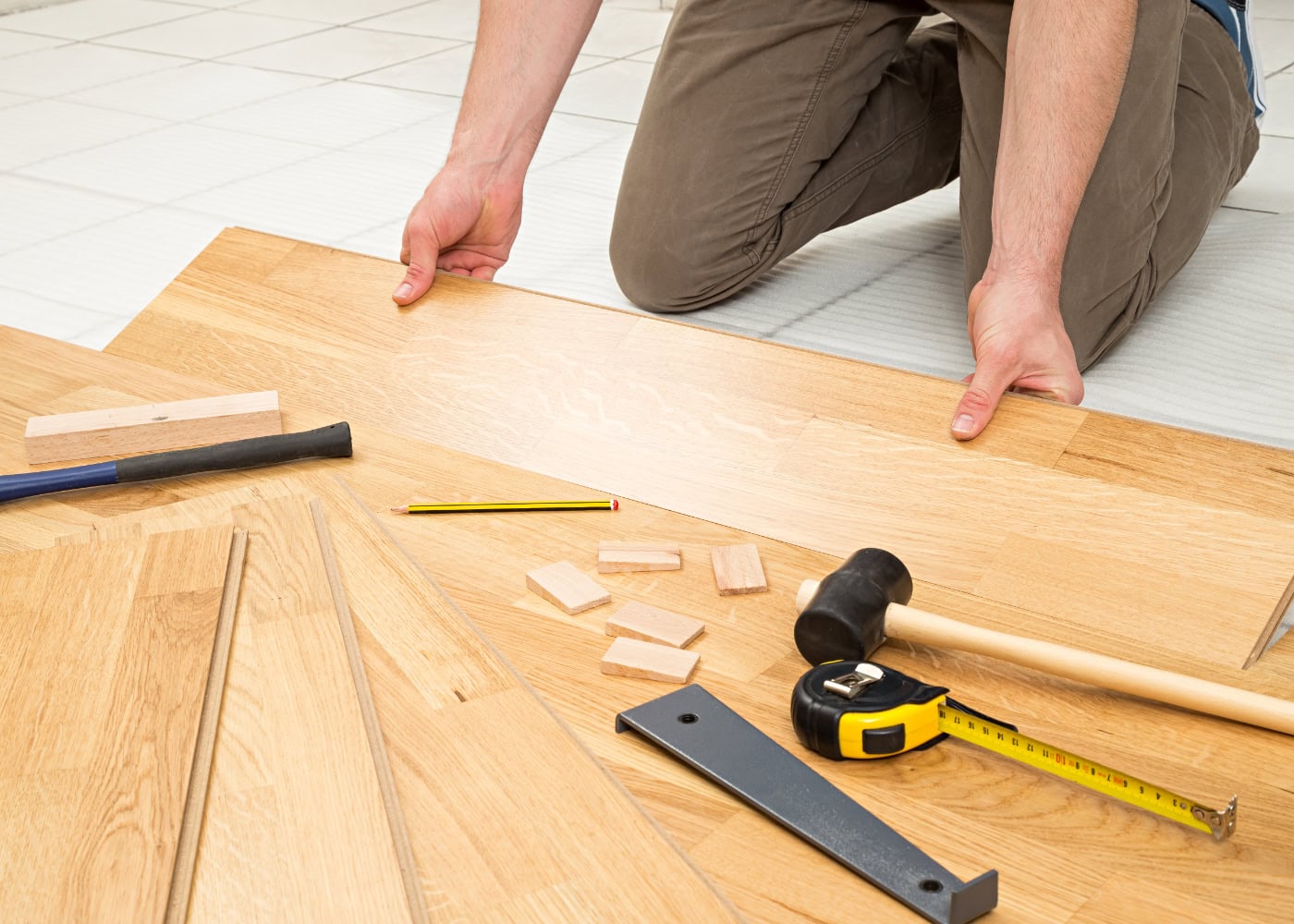 Handwerker verlegt Parkettboden in einem Wohnraum