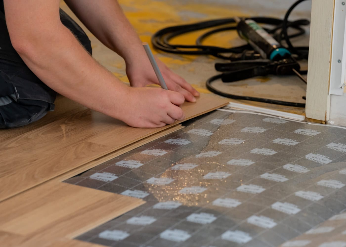 Handwerker markiert Laminatboden zum passgenauen Zuschneiden