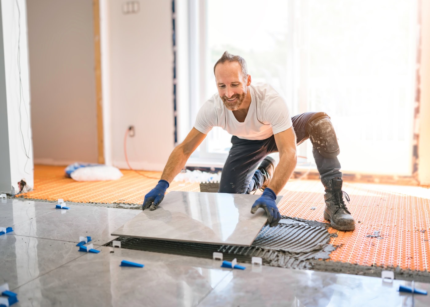 Handwerker verlegt großformatige Küchenfliesen auf dem Boden